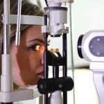 Patient or customer at slit lamp at optometrist or optician examining eyesight